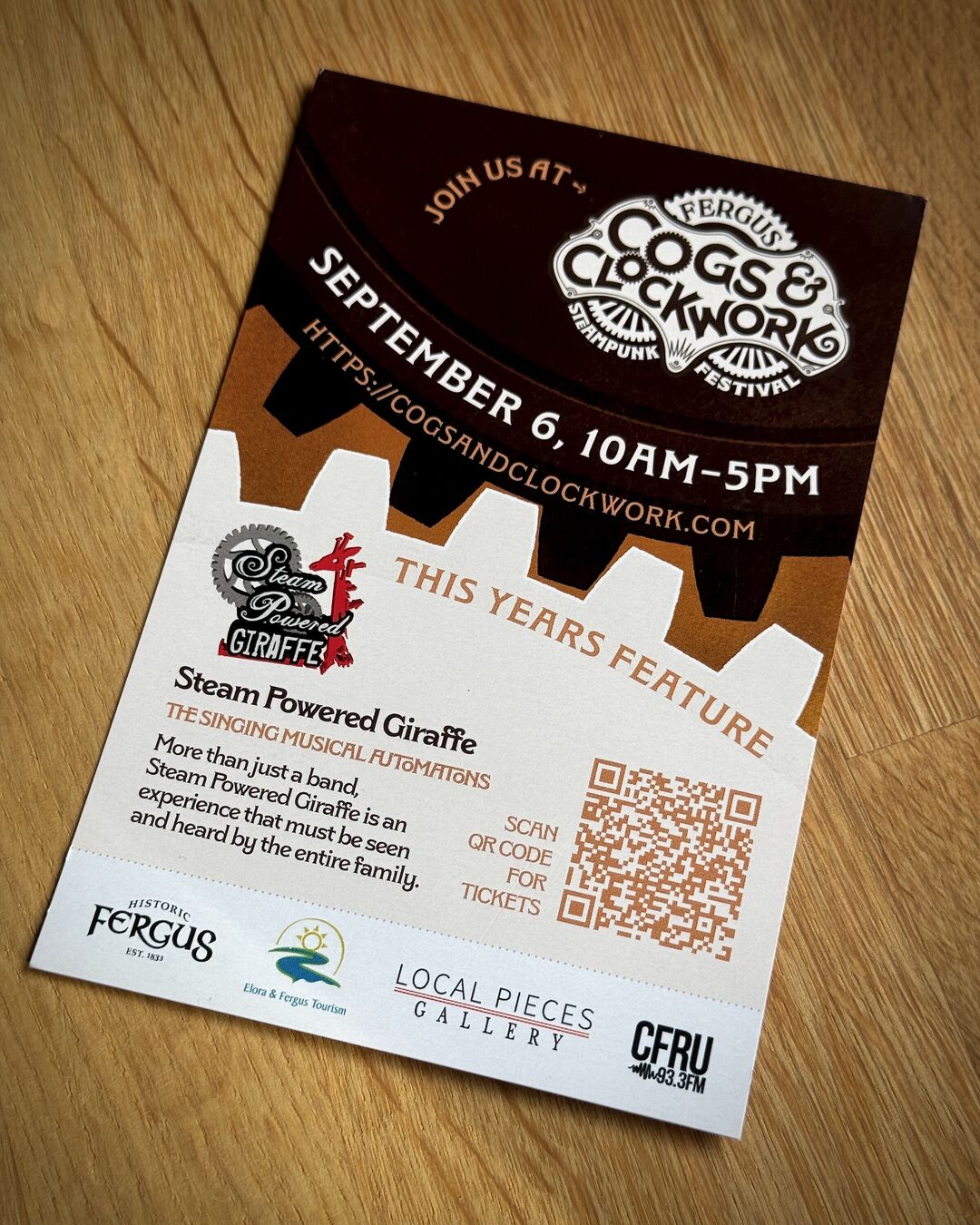 Join us at Cogs and Clockwork 2025 promotional postcard with two large intersecting gears in autumn colours. Event date, website link and logo displayed in upper gear. Lower gear shows event information for this years featured concert: Steam Powered Giraffe.