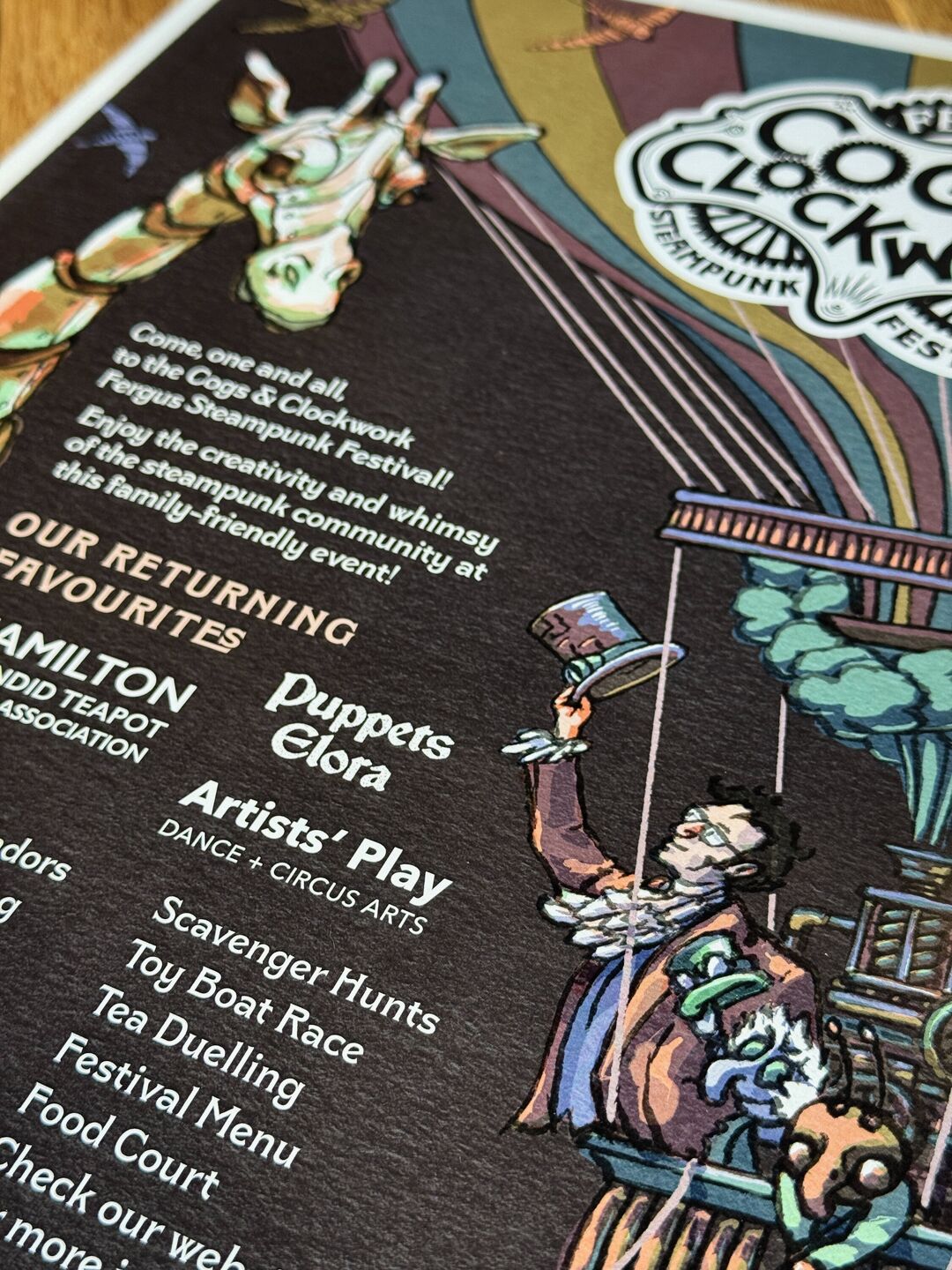 Centre right detail of the Cogs and Clockwork 2025 festival promotion illustrated poster focusing on the festival ringmaster saluting a mechanical giraffe from a floating hot air balloon.
