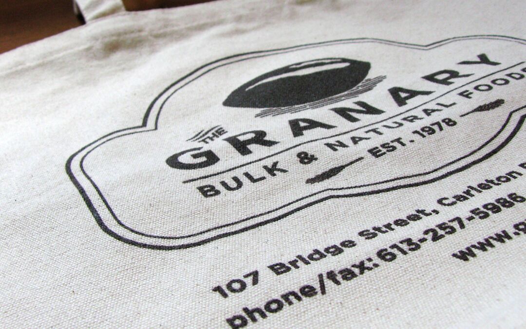 The Granary logo is printed on a white tote bag with text providing contact information and address.